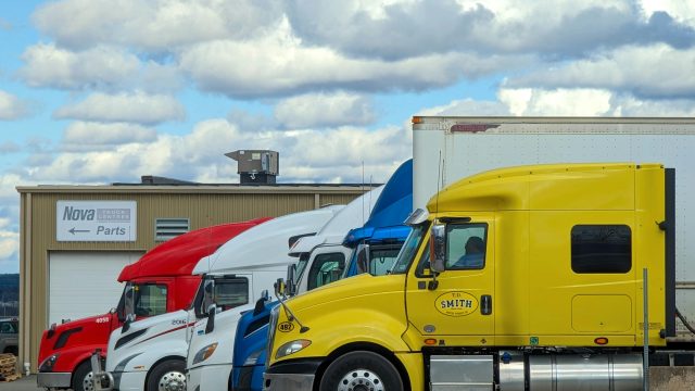 A vibrant lineup of semi trucks parked outside a Nova Truck Center in Truro, NS, Canada.